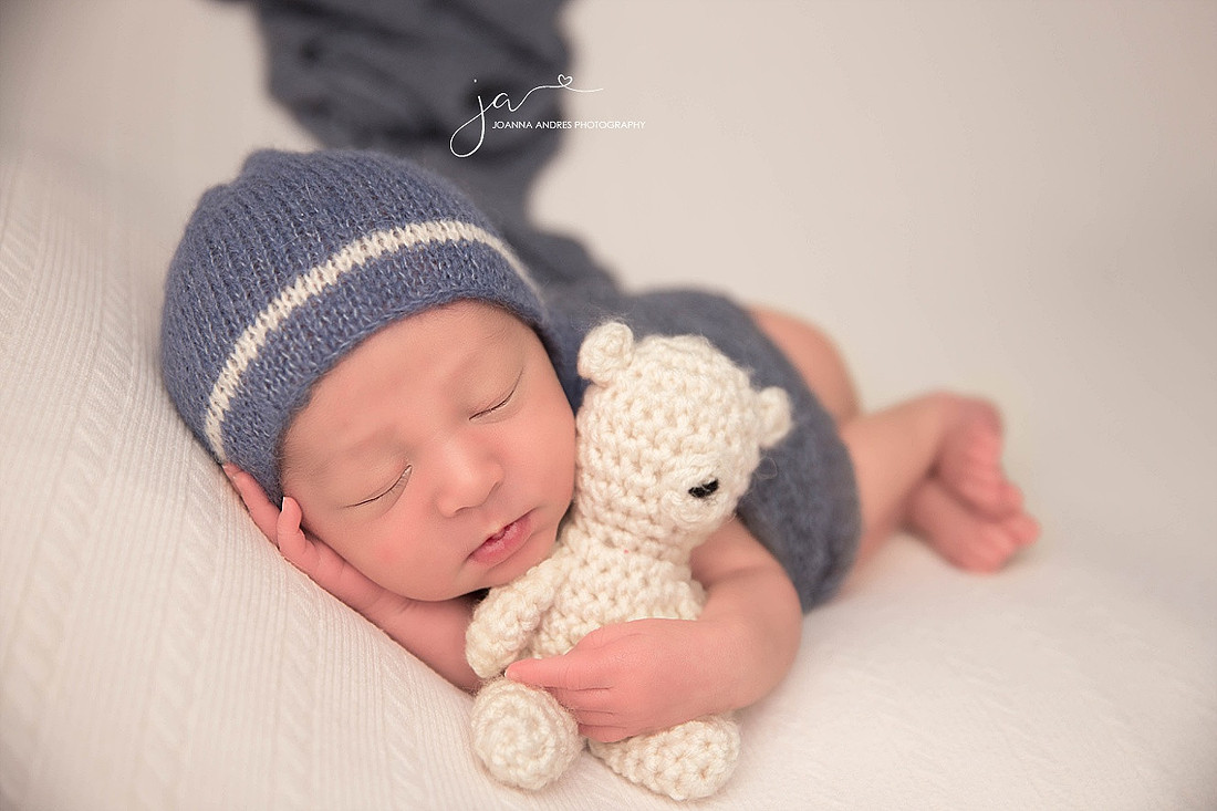 Side Laying Pose Baby Boy with lovey in a blue and white hat
