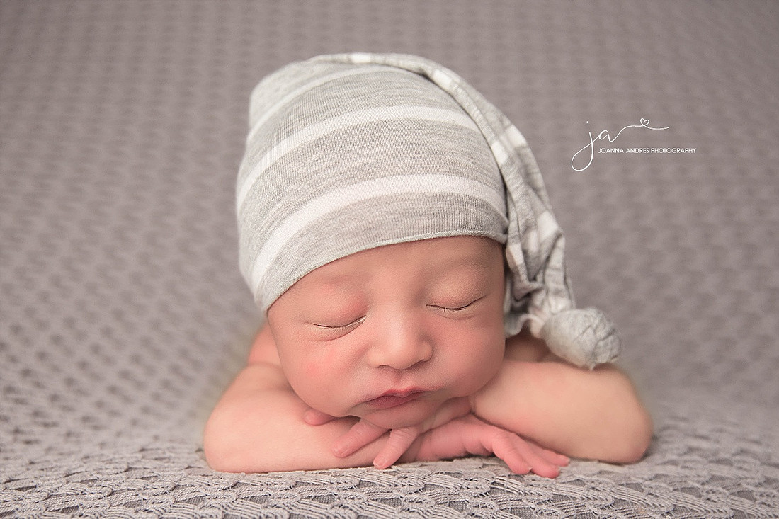 Newborn posed with hands folded under head