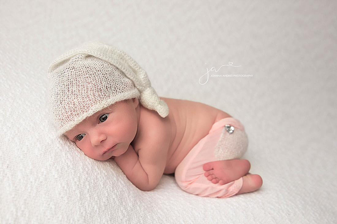 Newborn Baby Girl wide awake with white hat and pink pants