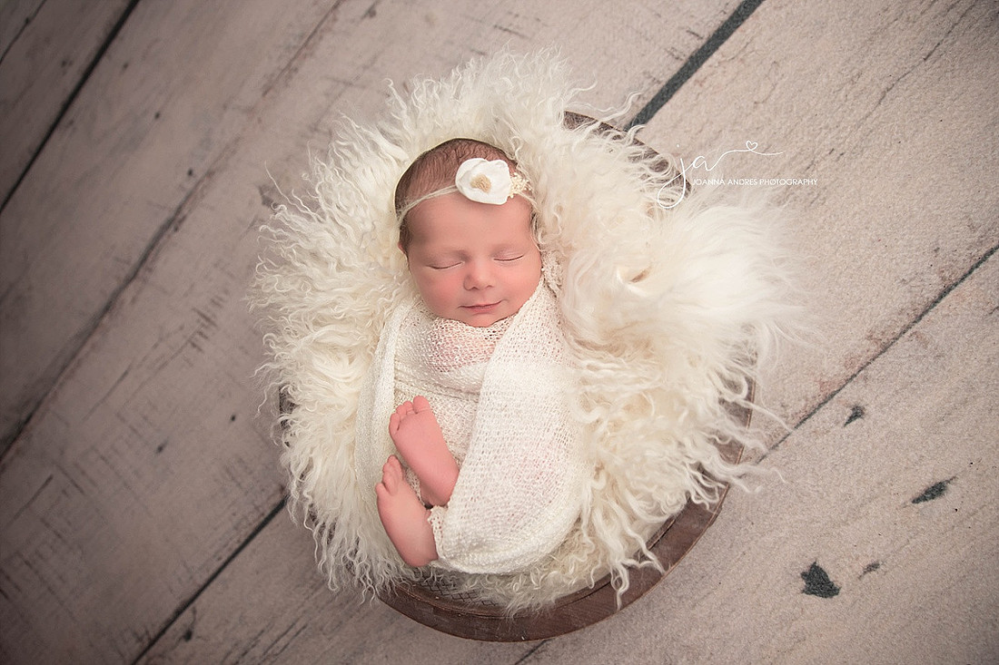 Newborn Baby Girl in prop wrapped in white with white headband