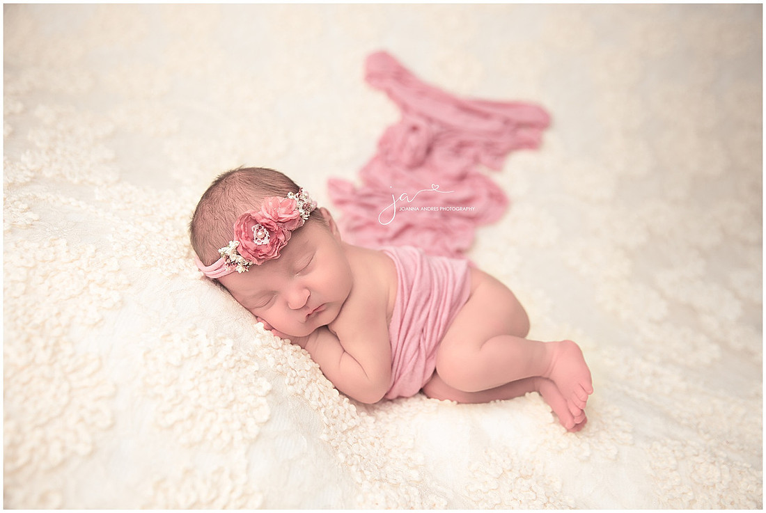 Newborn Baby Girl Side Laying Pose draped with pink fabric