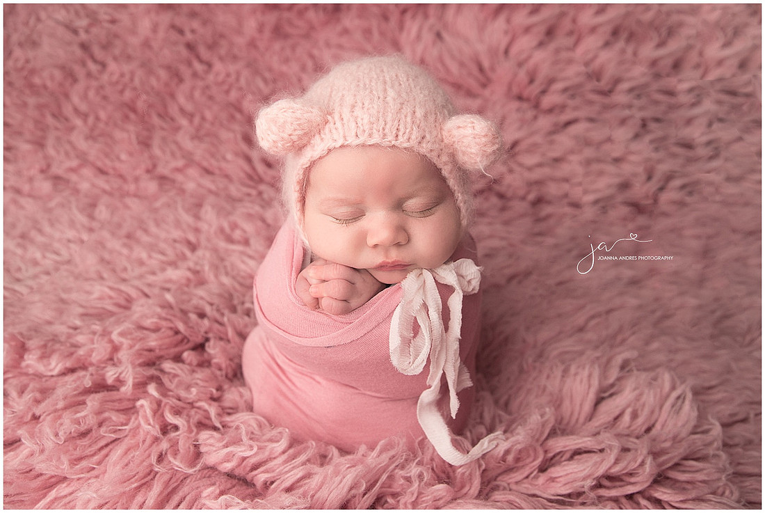 Newborn Baby Wrapped in Pink with Pink Flokati rug as backdrop
