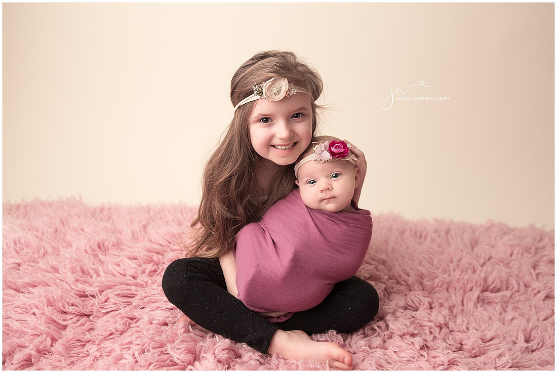 Newborn Baby Girl being held by her big sister