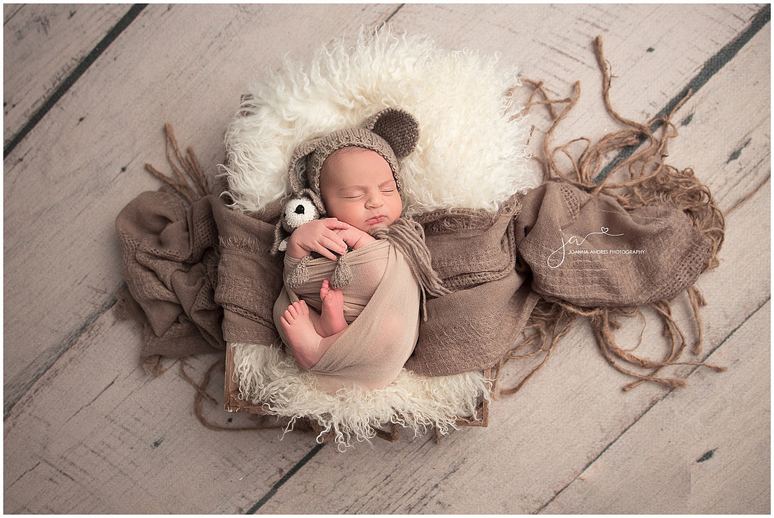 Newborn Baby Boy in a prop holding lovey in browns