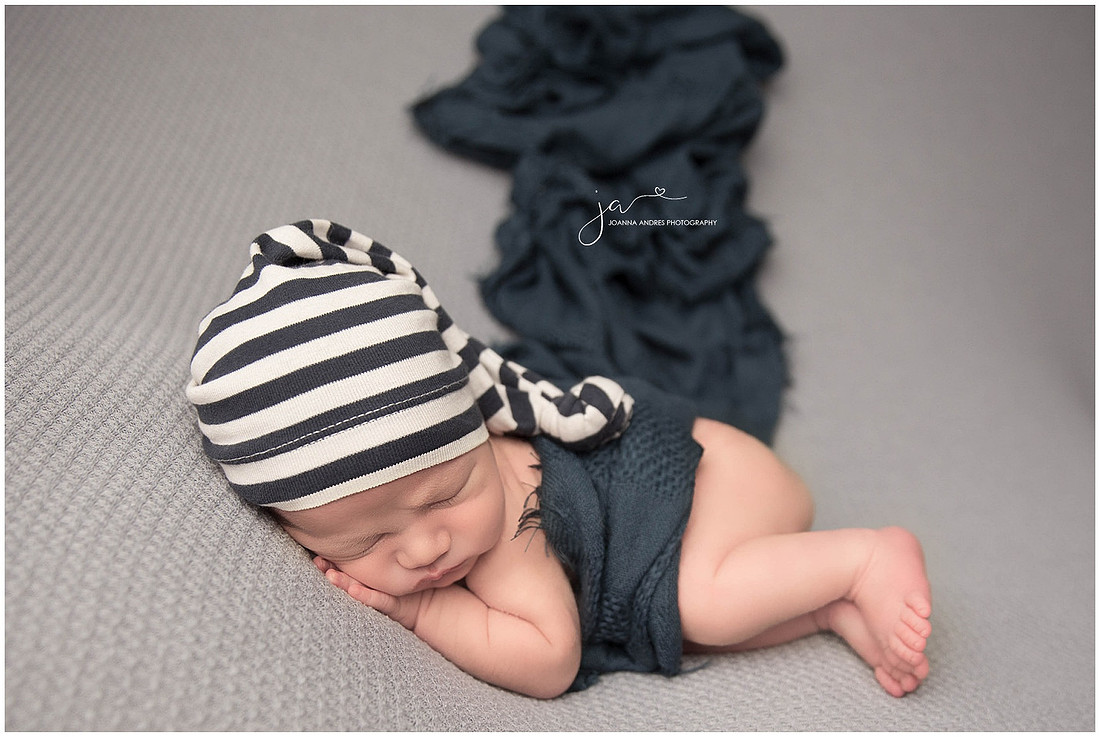 Baby Micah side laying pose with Navy Blue Hat