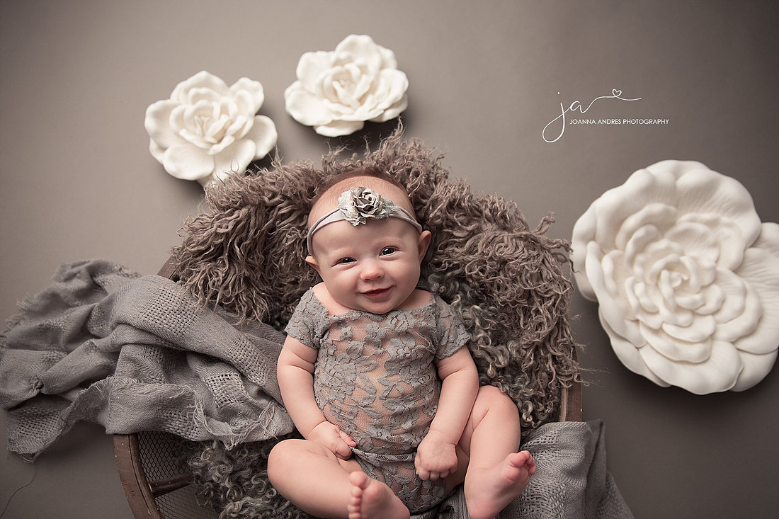 Baby Emma wearing gray lace in a basket 3 month session with flower surrounding her