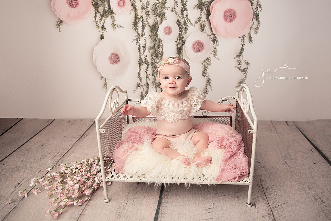 Baby Girl in Pink Dress sitting on a bed