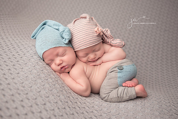 Newborn Twins stacked on eachother baby girl smiling