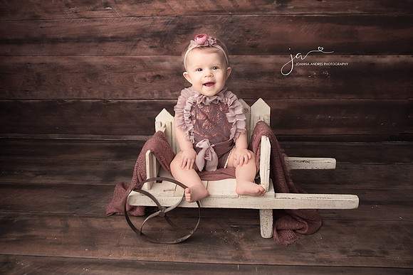 Baby Girl in Mauves stting in a wagon prop