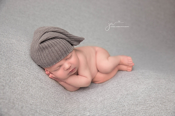 Newborn Baby Side Laying POse with Gray hat and laying on gray blanket