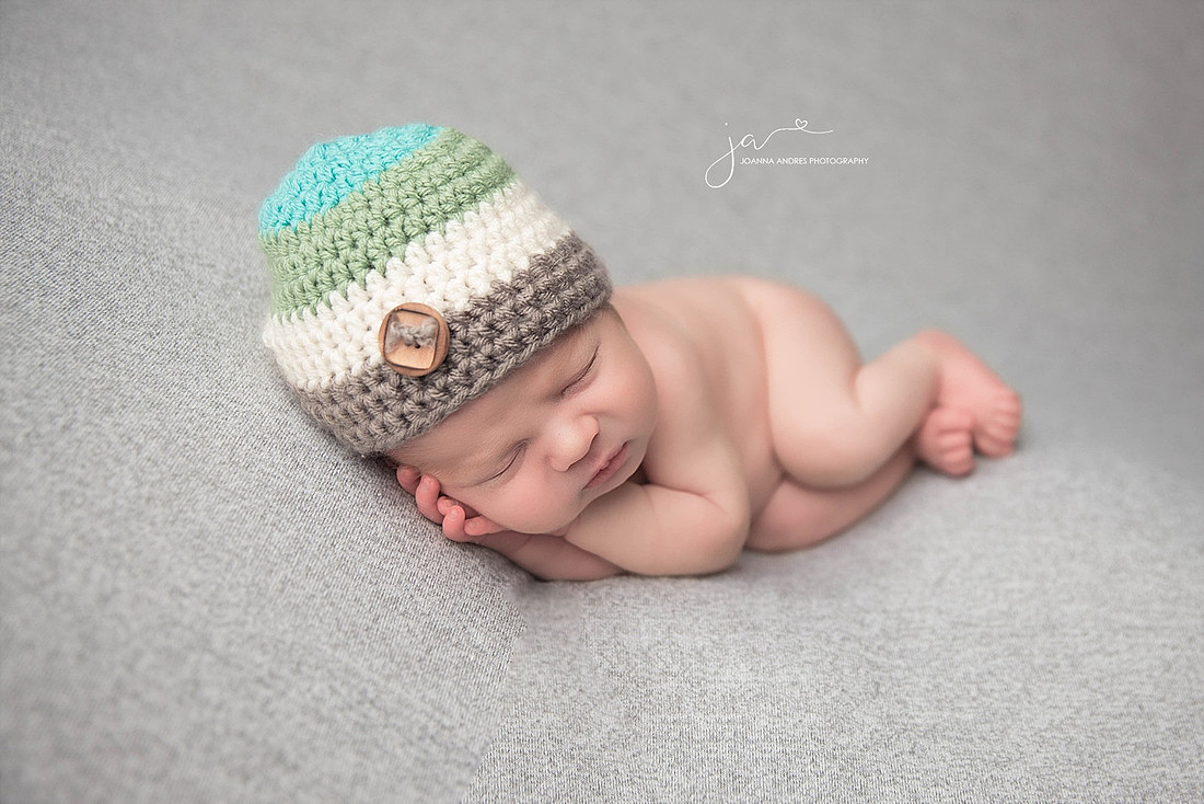 NEwborn Baby Boy Side Laying Pose with Gray, White, Green and Teal hat