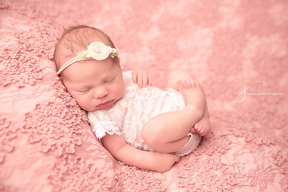 Newborn Baby Girl Huck Finn Pose baby in a lace romper layng on pink lace blanket