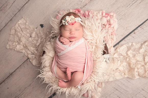 Cute newborn Girl wrapped in pinks in a prop