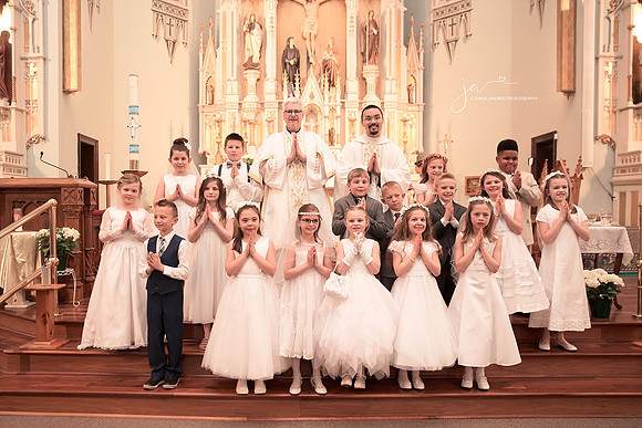 First Communion group shot of all kids in church with priest