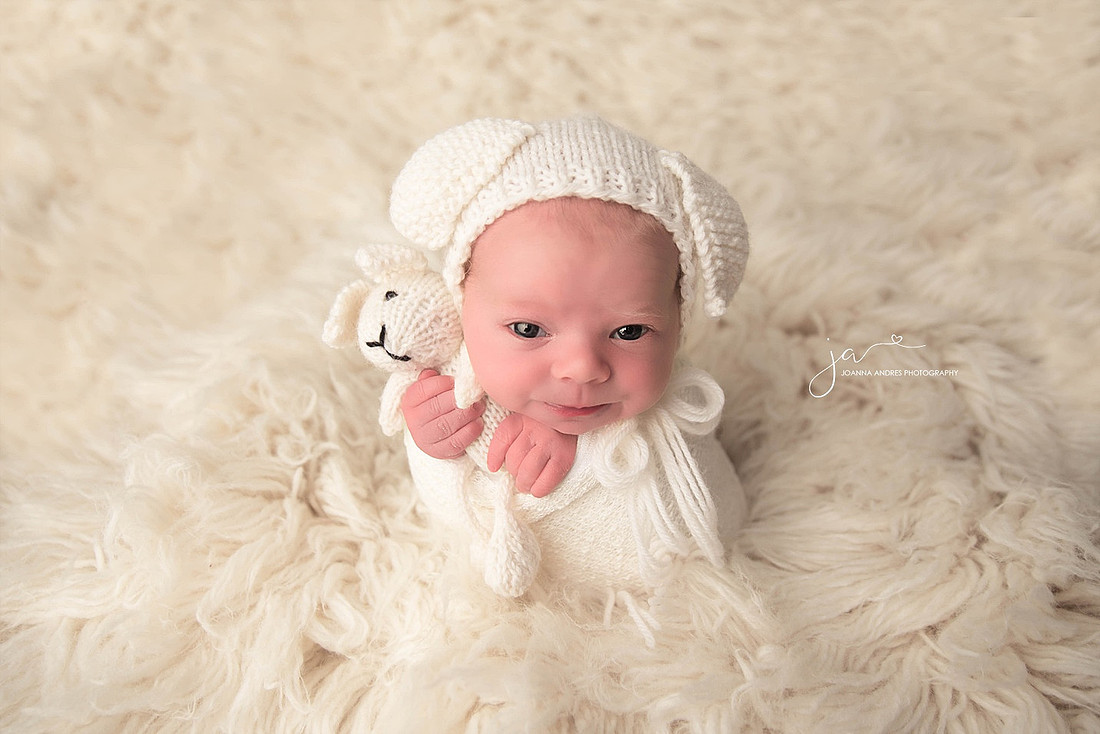 Newborn Baby Girl wide eyed holding lovey in whites