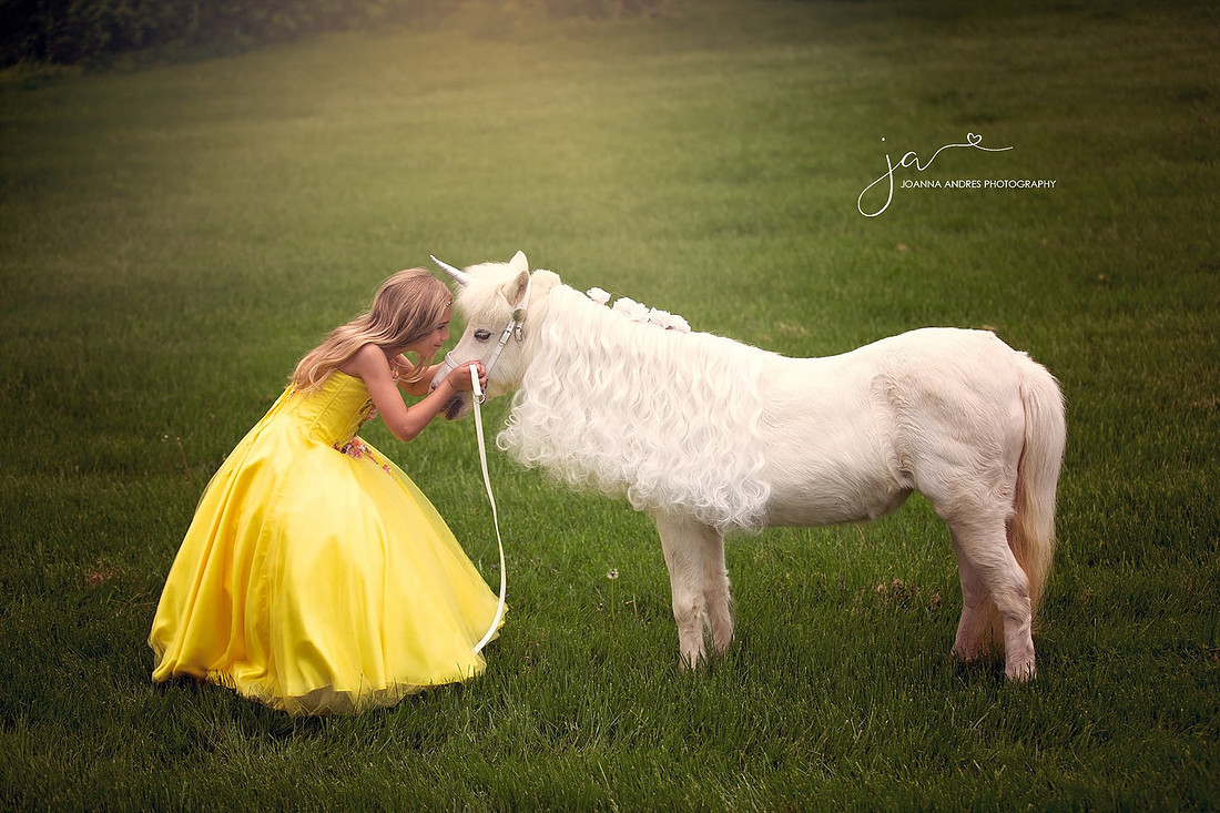 Girl kissing unicorn in a yellow gown