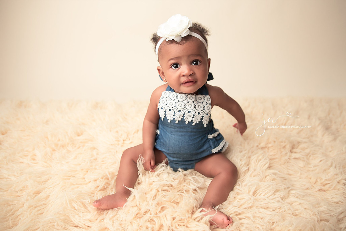 Baby girl sitting up with blue romper