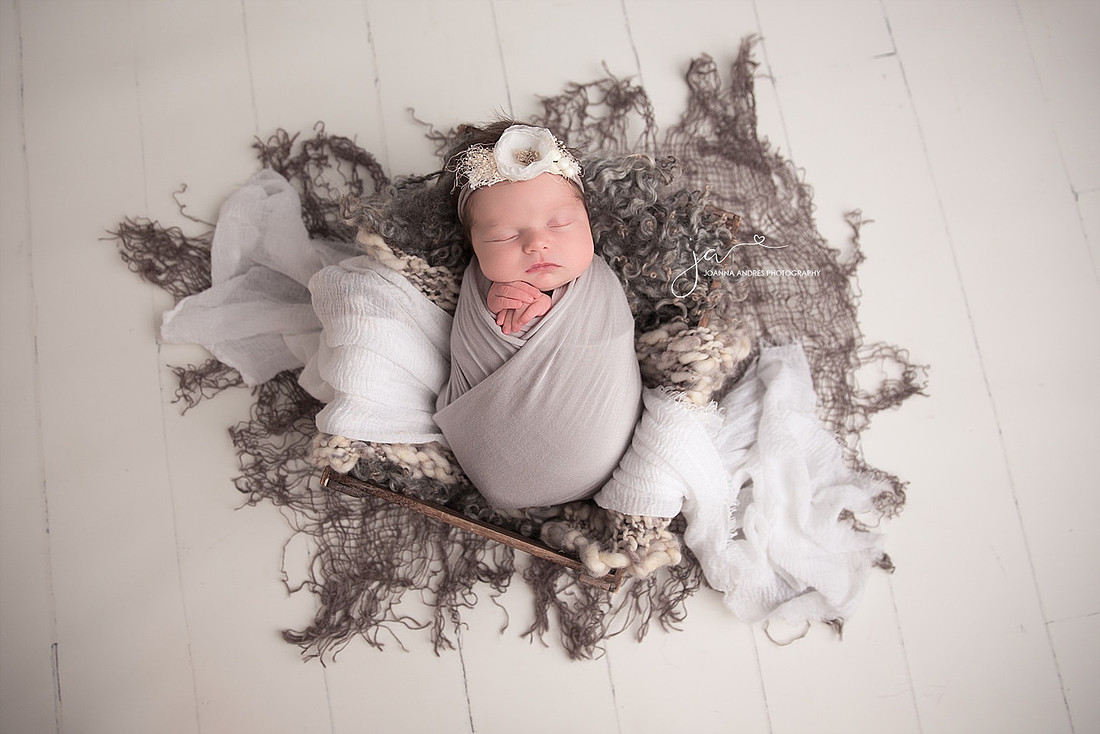 Baby in prop with grays and layers with white backdrop