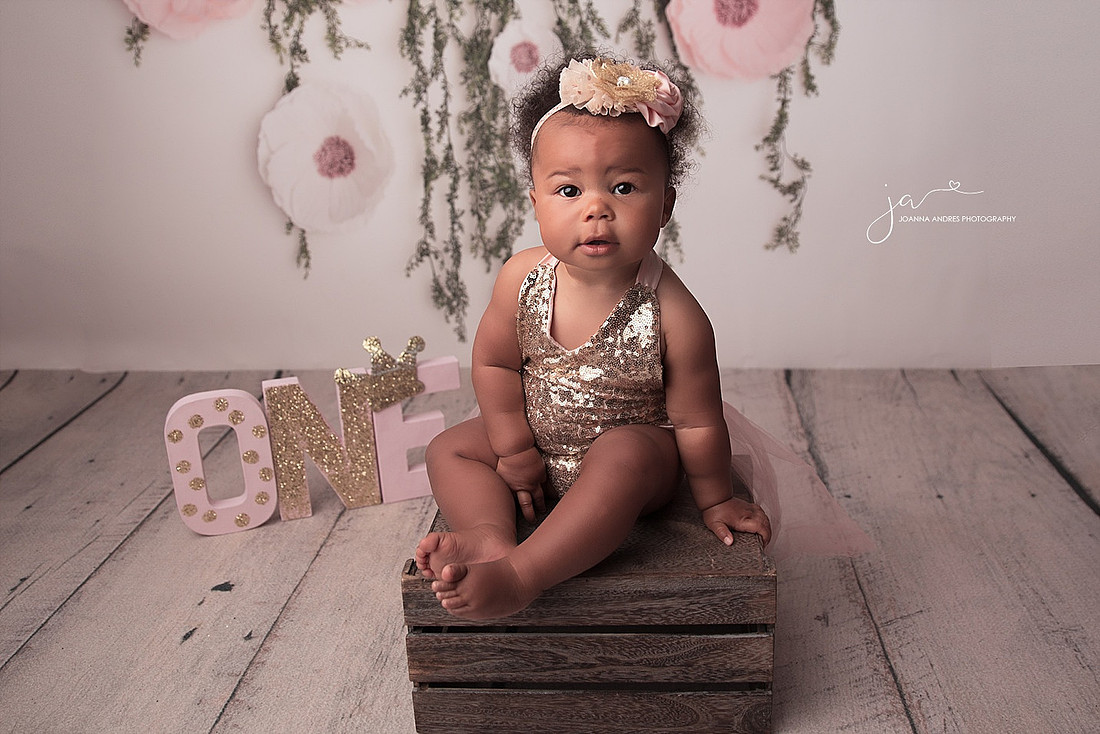 Baby girl in gold sequence sitting on a bench