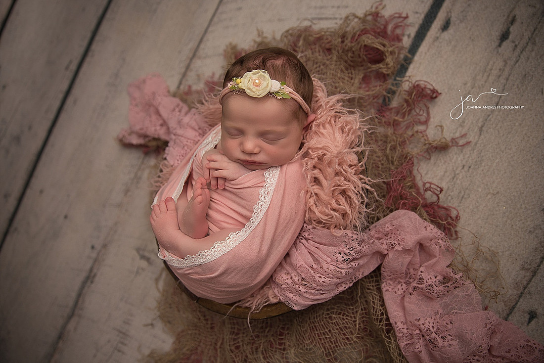 Baby in a basket wearing pink