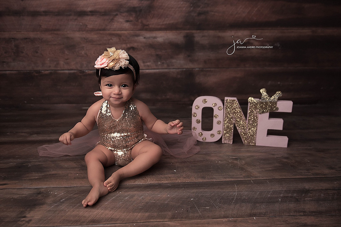 Baby girl sitting with ONE letters