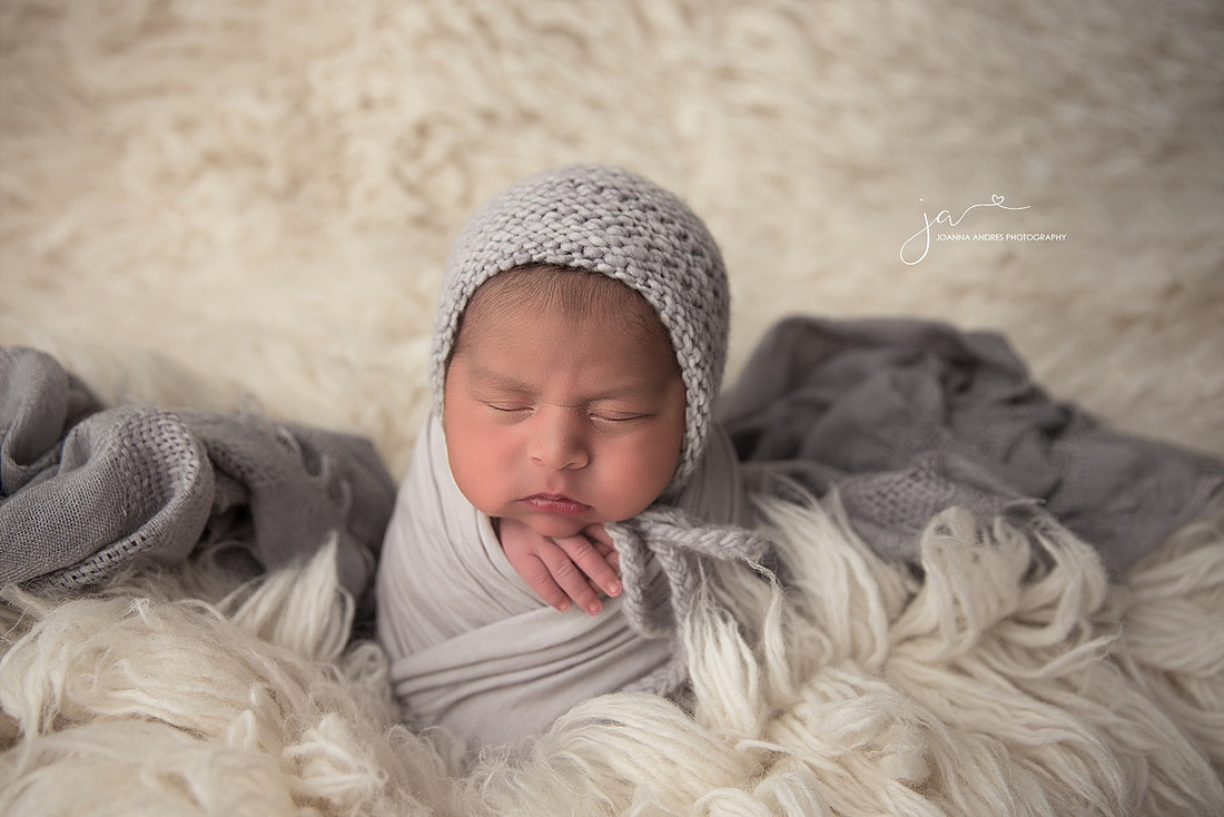 Newborn Baby Boy wrapped in light gray with White Flokati rug