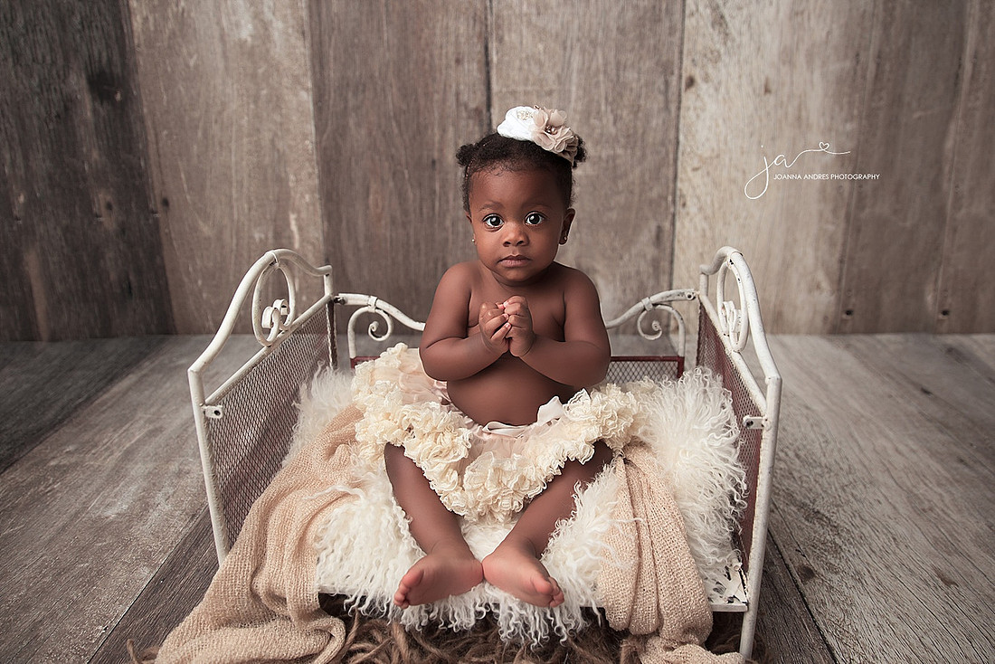 Baby girl in gold tutu sitting on a bed