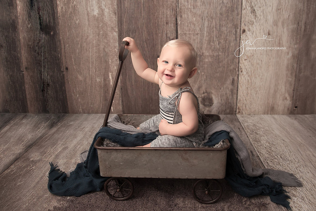 Baby boy in a wagon smiling.