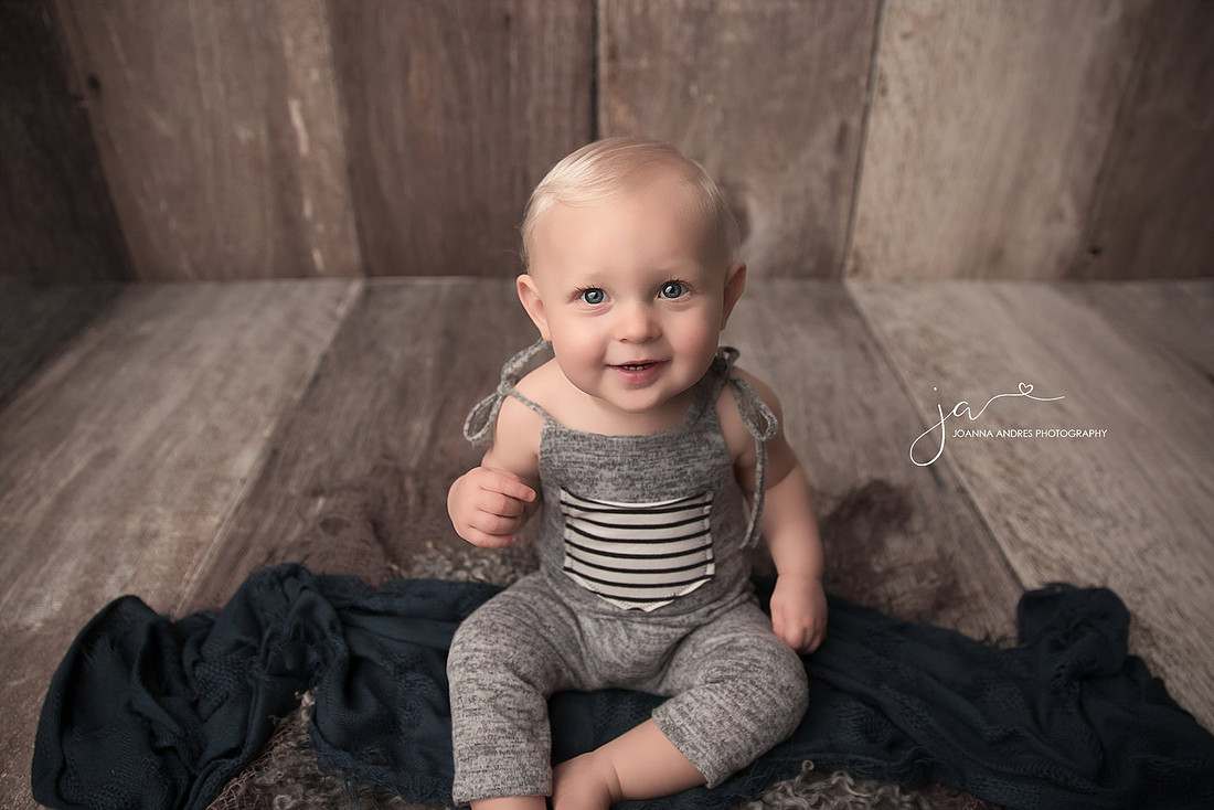 Baby Boy sitting and smiling wearing blue romper
