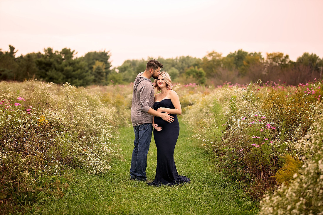 Husband Kissing wife on forehead in a field of wild flowers