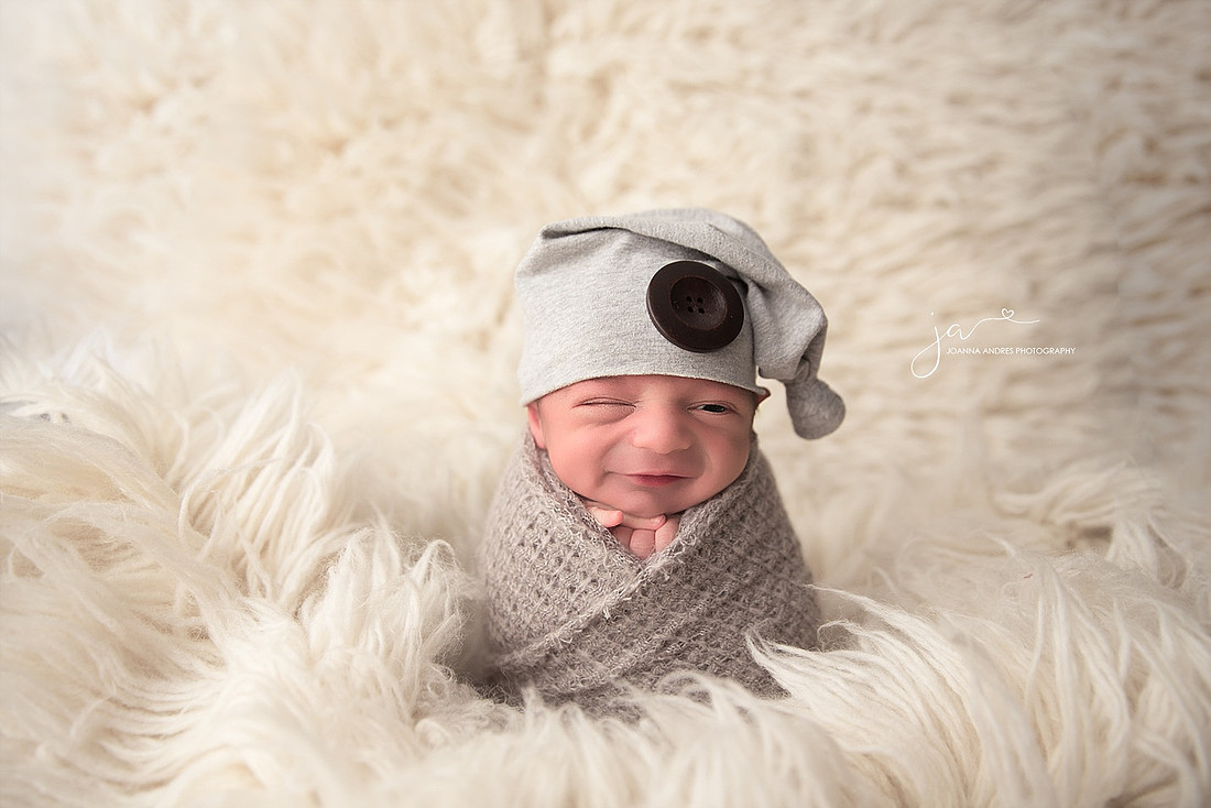 Baby Boy wrapped in gray with white flokati rug smiling