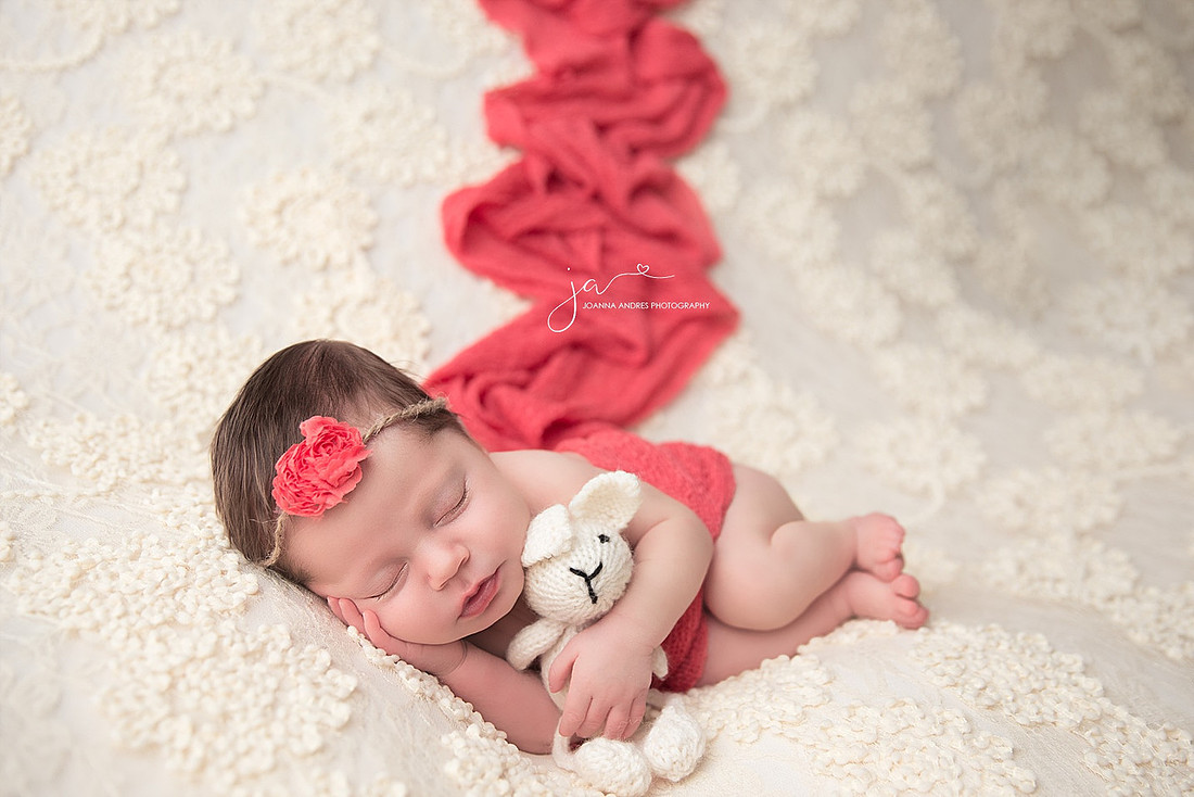 Side Laying Pose of Baby holding Lovey with Coral accent colors